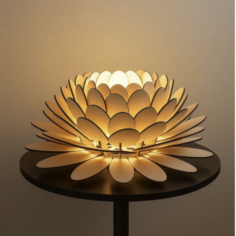 Lampe fleur de lotus artisanale en bois diffusant une lumière chaude et douce, posée sur une table noire dans une ambiance minimaliste.